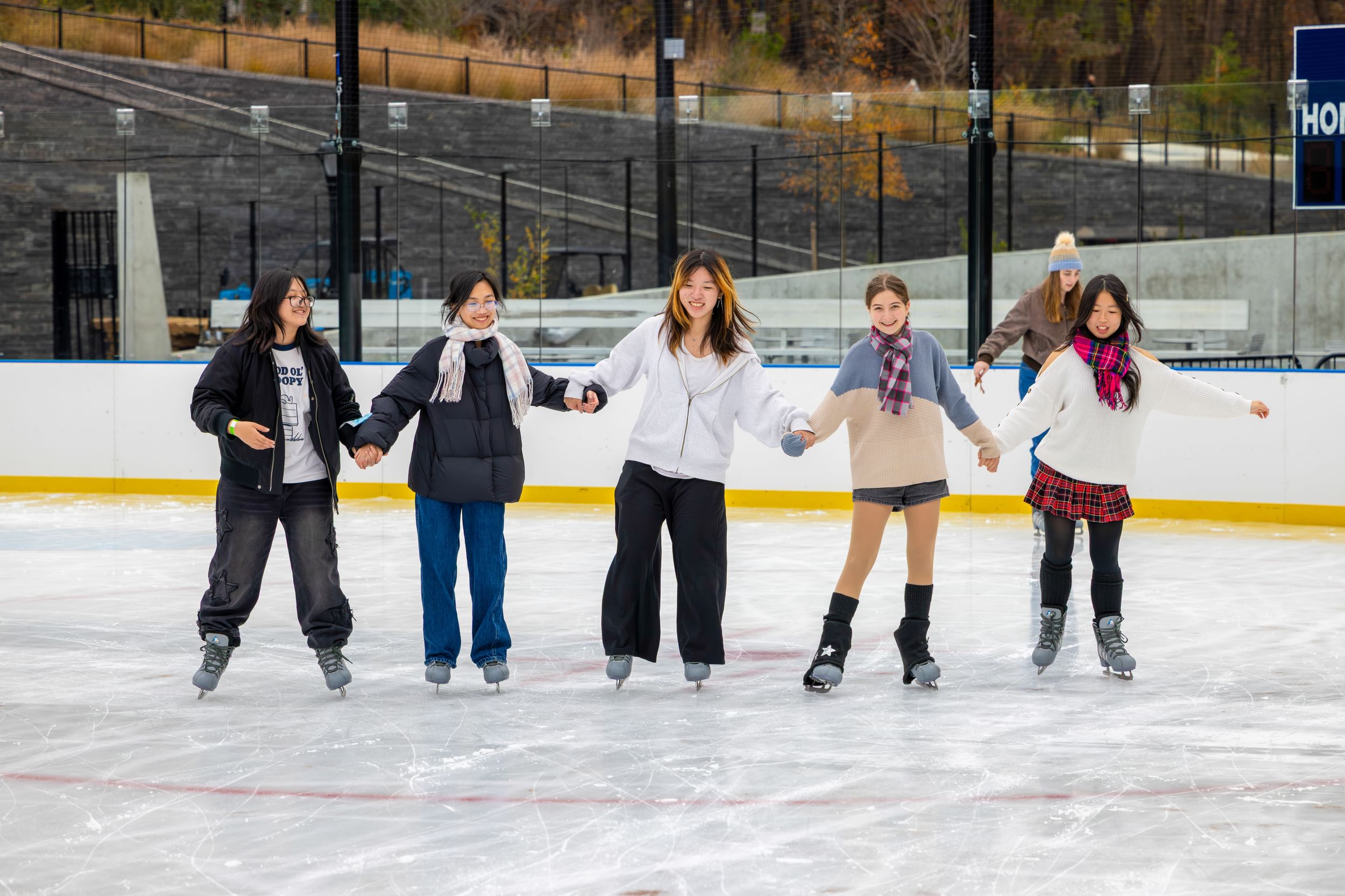 Young people holding hands while they skate on the Gottesman Ice Rink at the Davis Center in Harlem, NYC