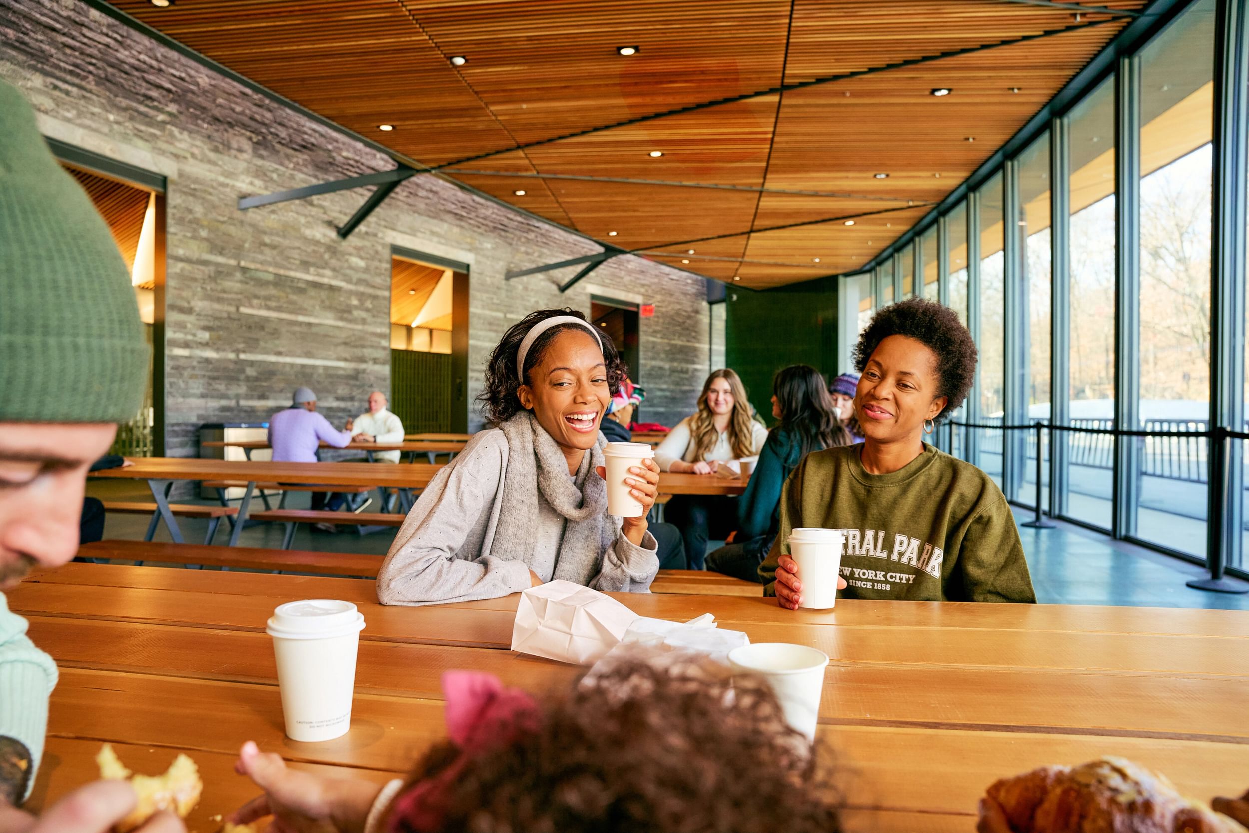 Visitors enjoying hot drinks and pastries in the indoor gathering space of the Davis Center, Harlem, New York City