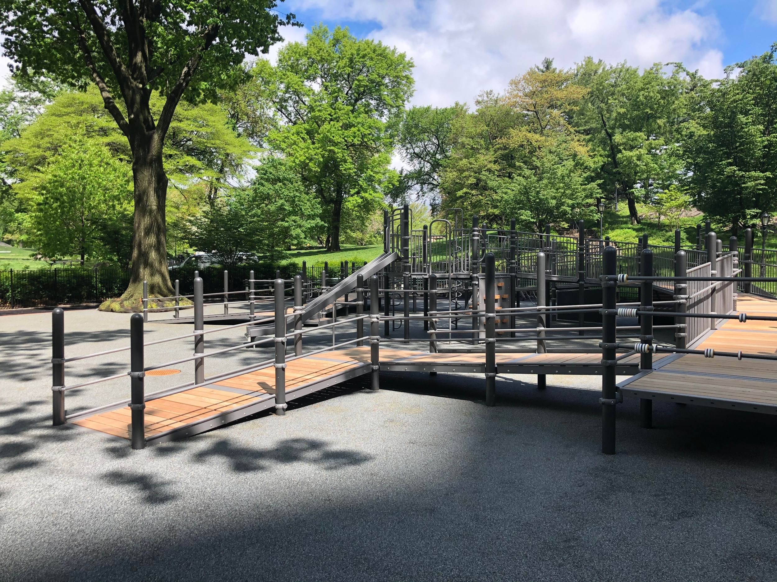 The playground is nested at the edge of a green, tree-lined landscape.